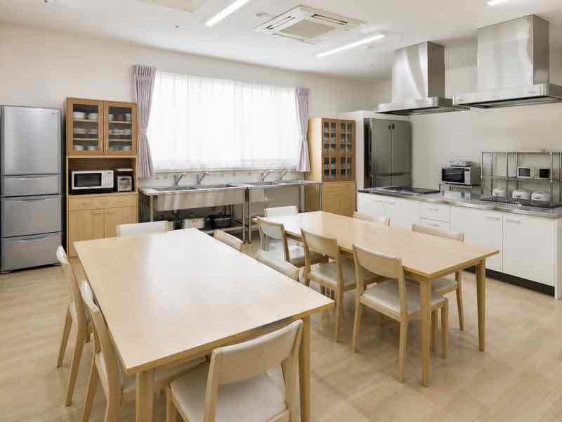 調理台や冷蔵庫、食卓を備えた明るく清潔な共用キッチン