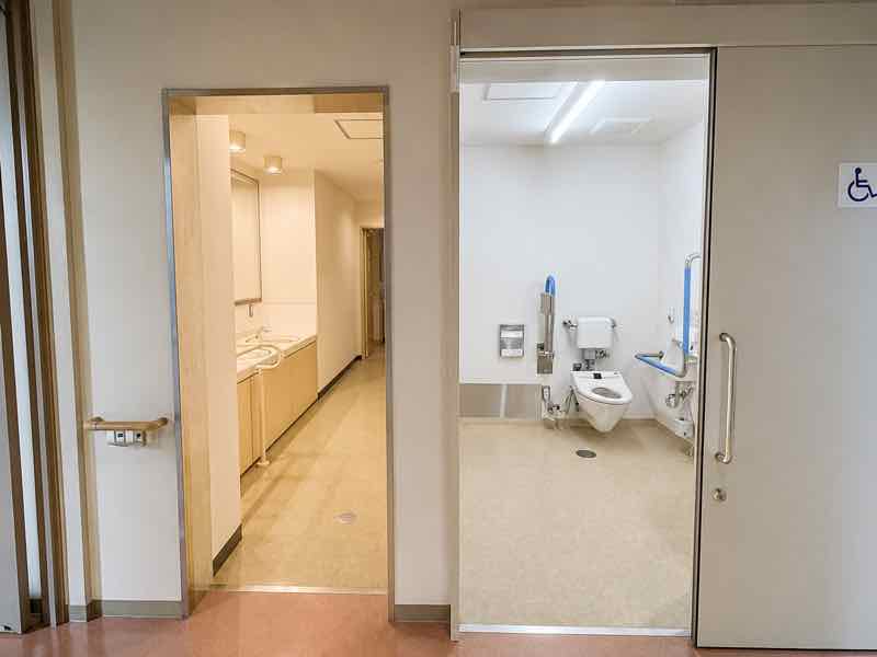洗面台と手すり付きトイレを備えた明るい衛生設備